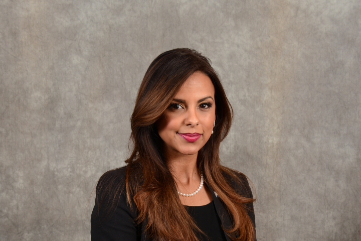 Latina woman executive in black suit against grey background