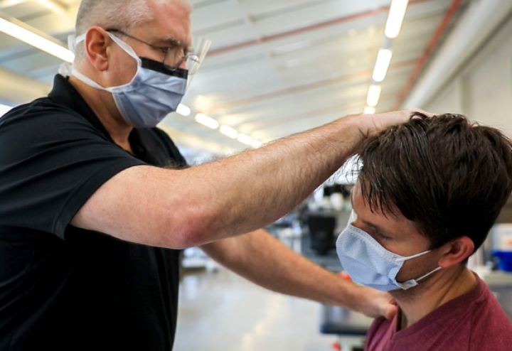 Man in mask provides physical therapy to younger man in mask sitting down