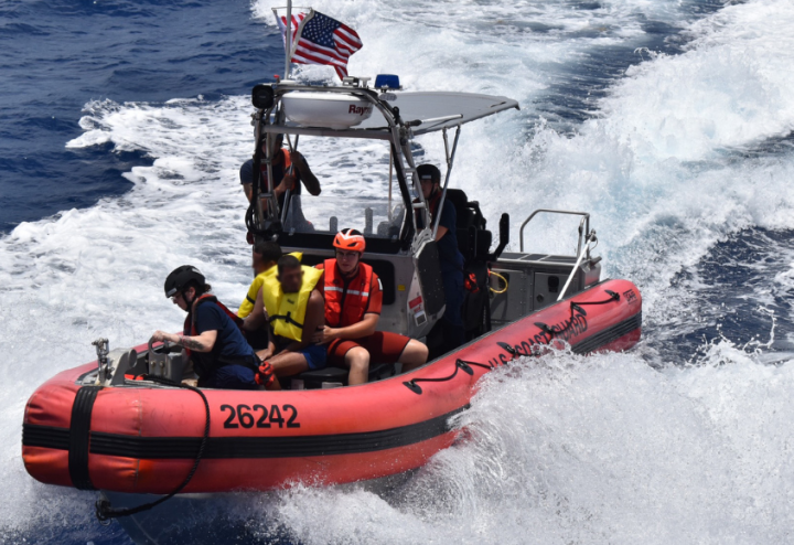 Five people ride a Coast Guard boat