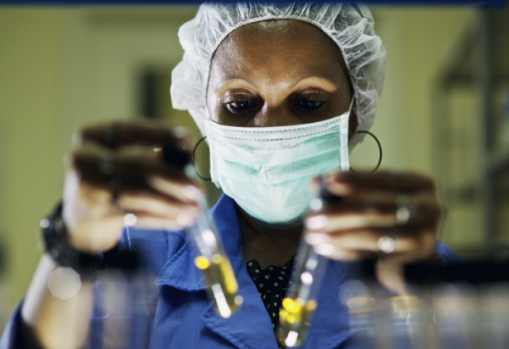 Black woman in mask holds up test tubes