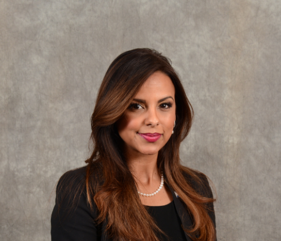 Latina woman executive in black suit against grey background